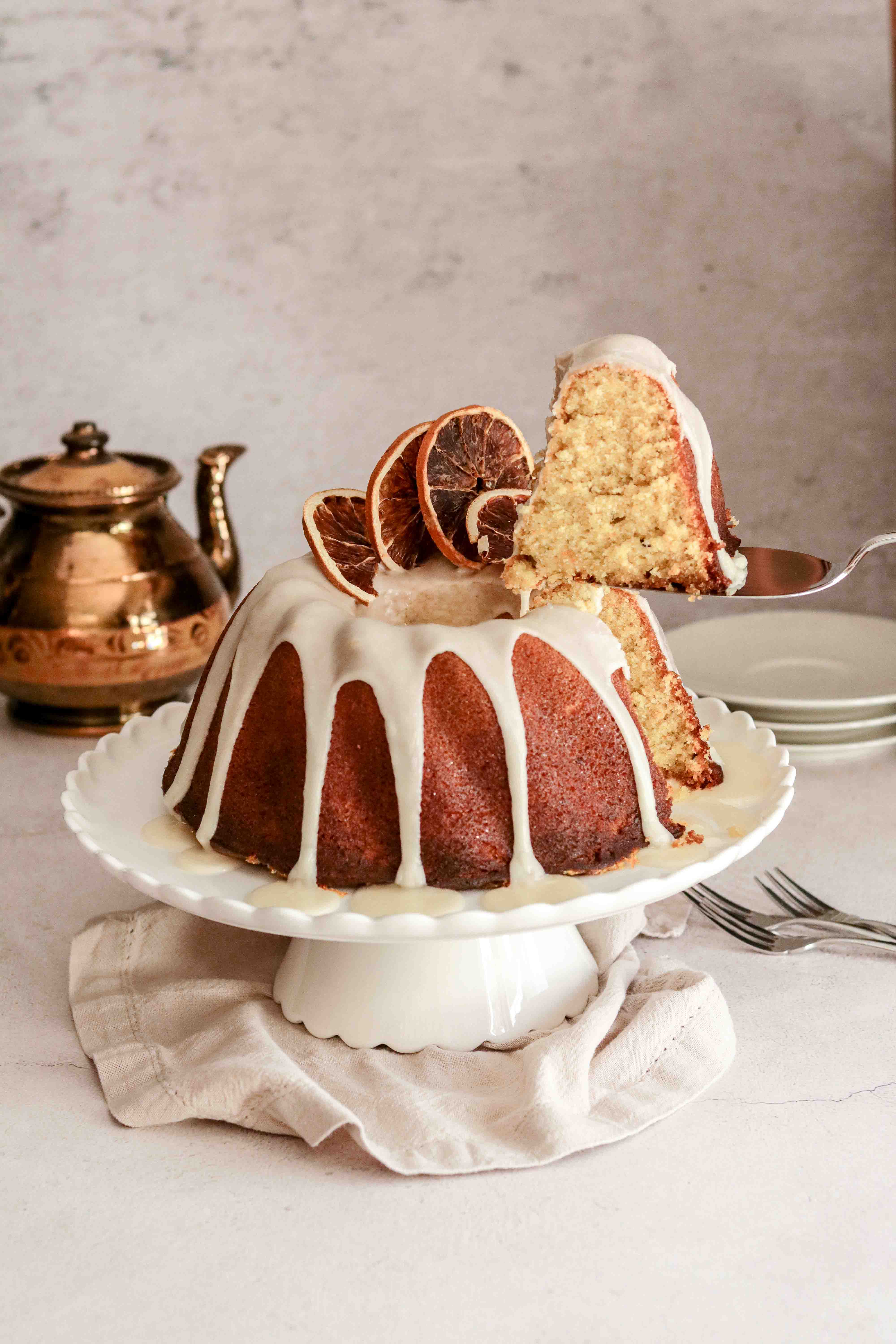 Orange drizzle bundt cake on a white cake stand