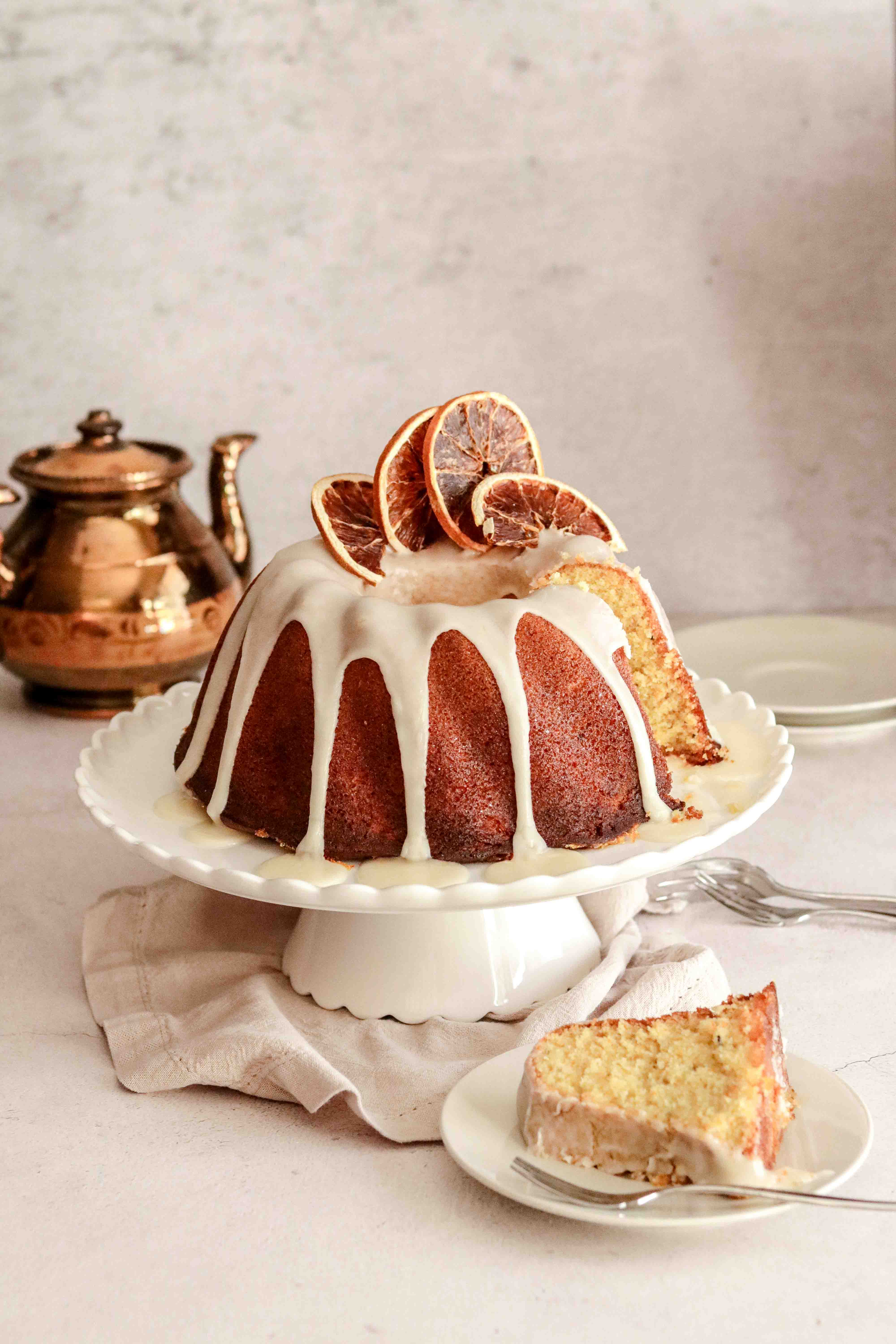 Orange drizzle bundt cake on a white cake stand