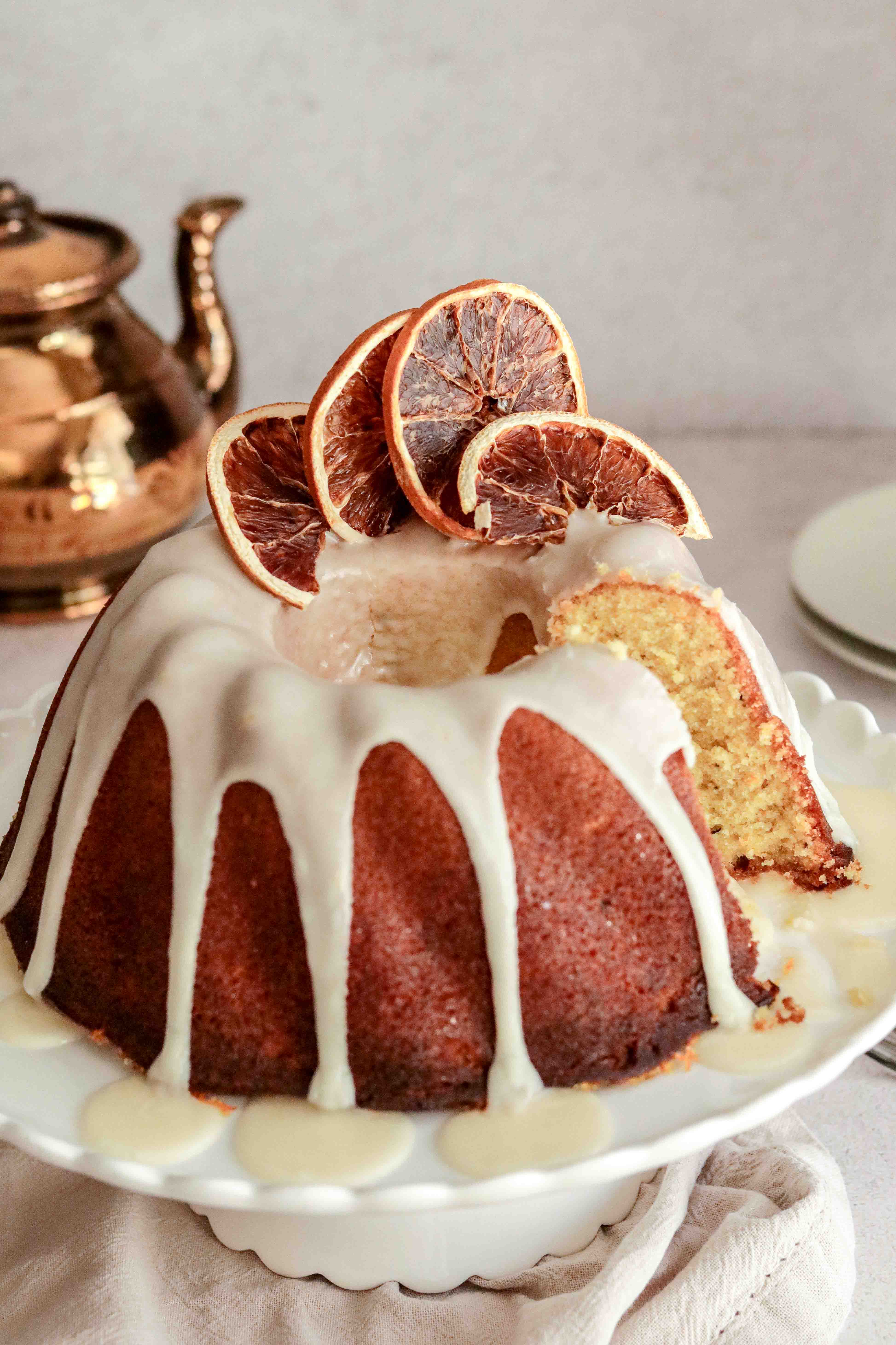 Orange drizzle bundt cake on a white cake stand