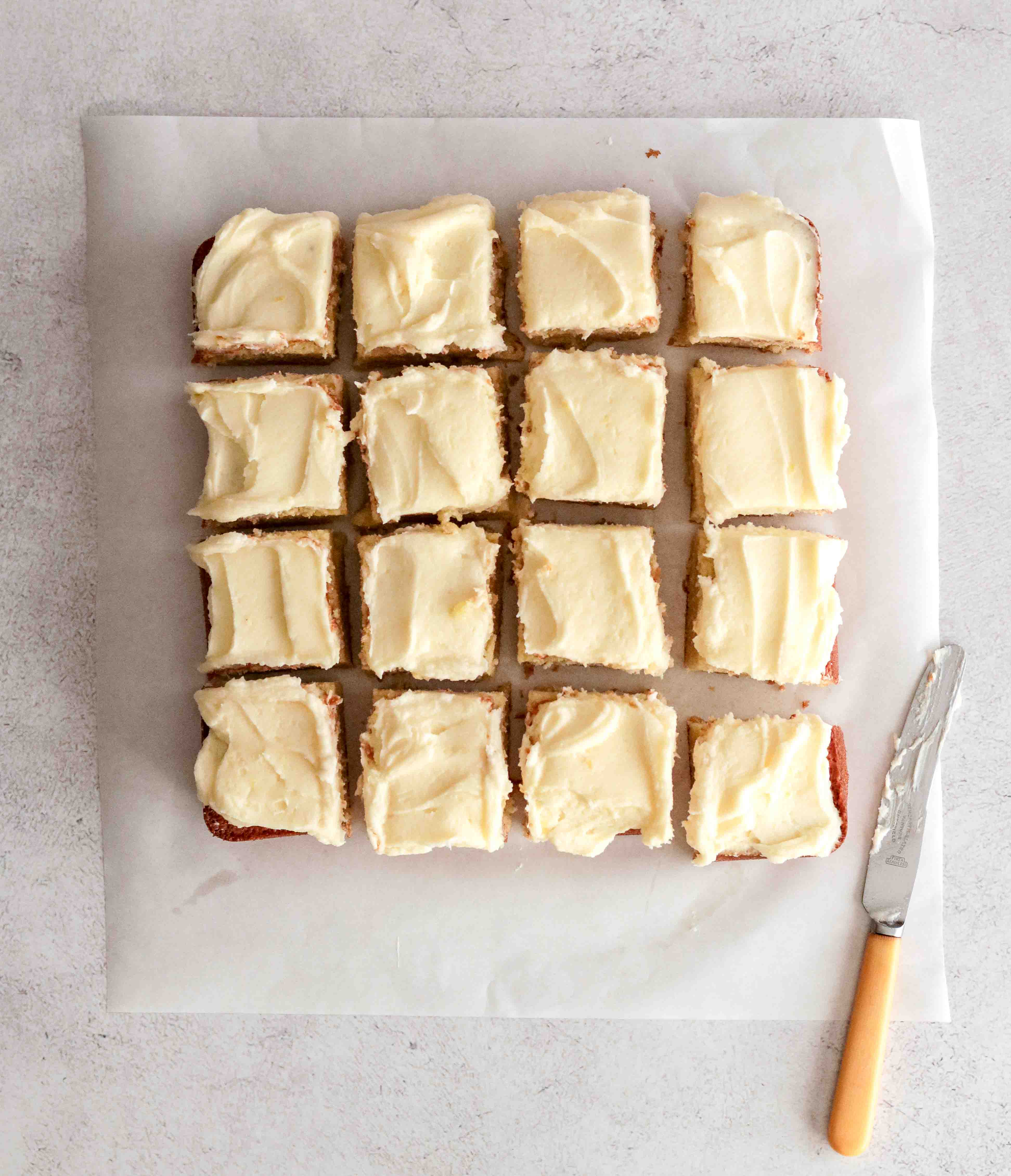 An iced lemon tray cake cut into squares