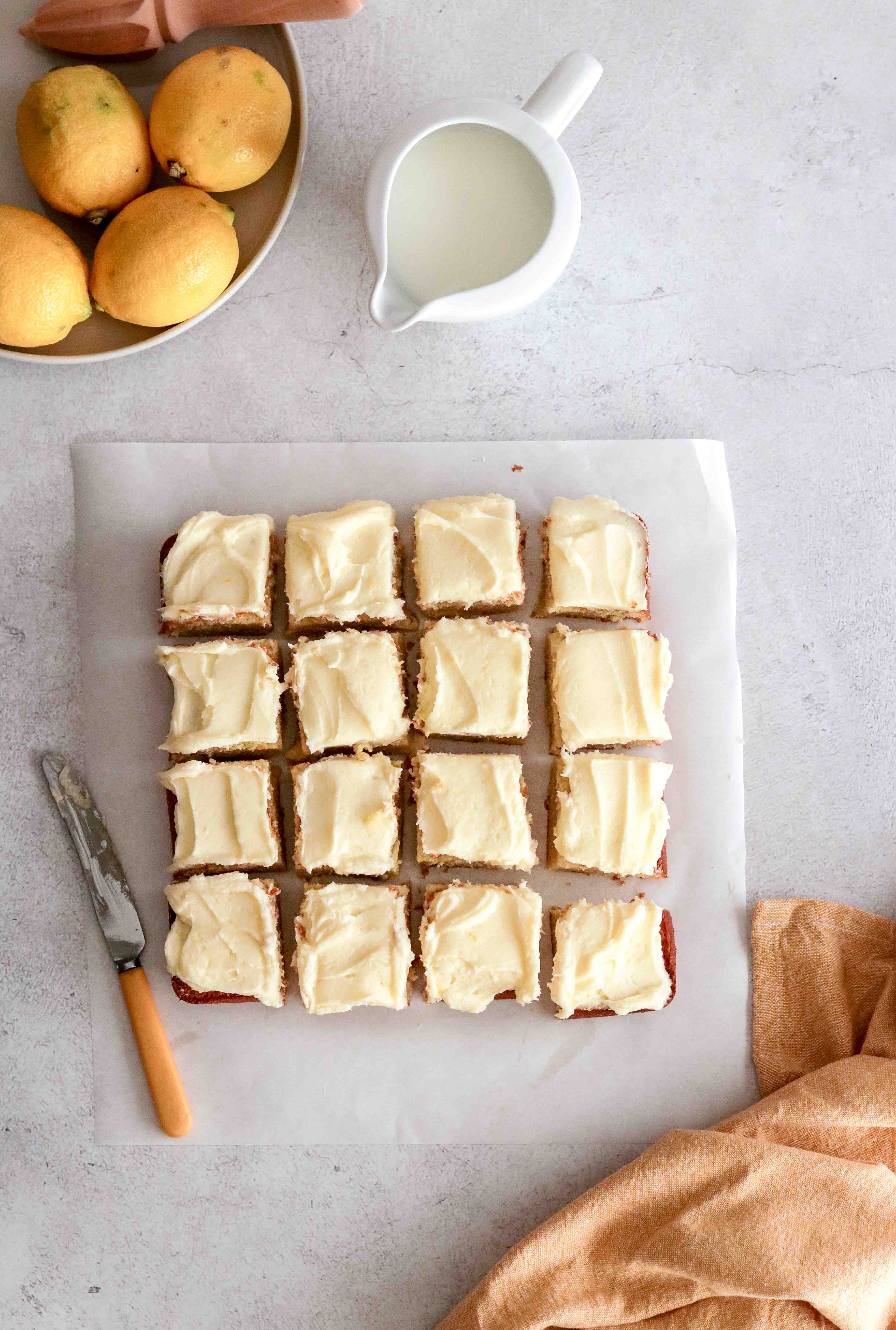 An iced lemon tray cake cut into squares