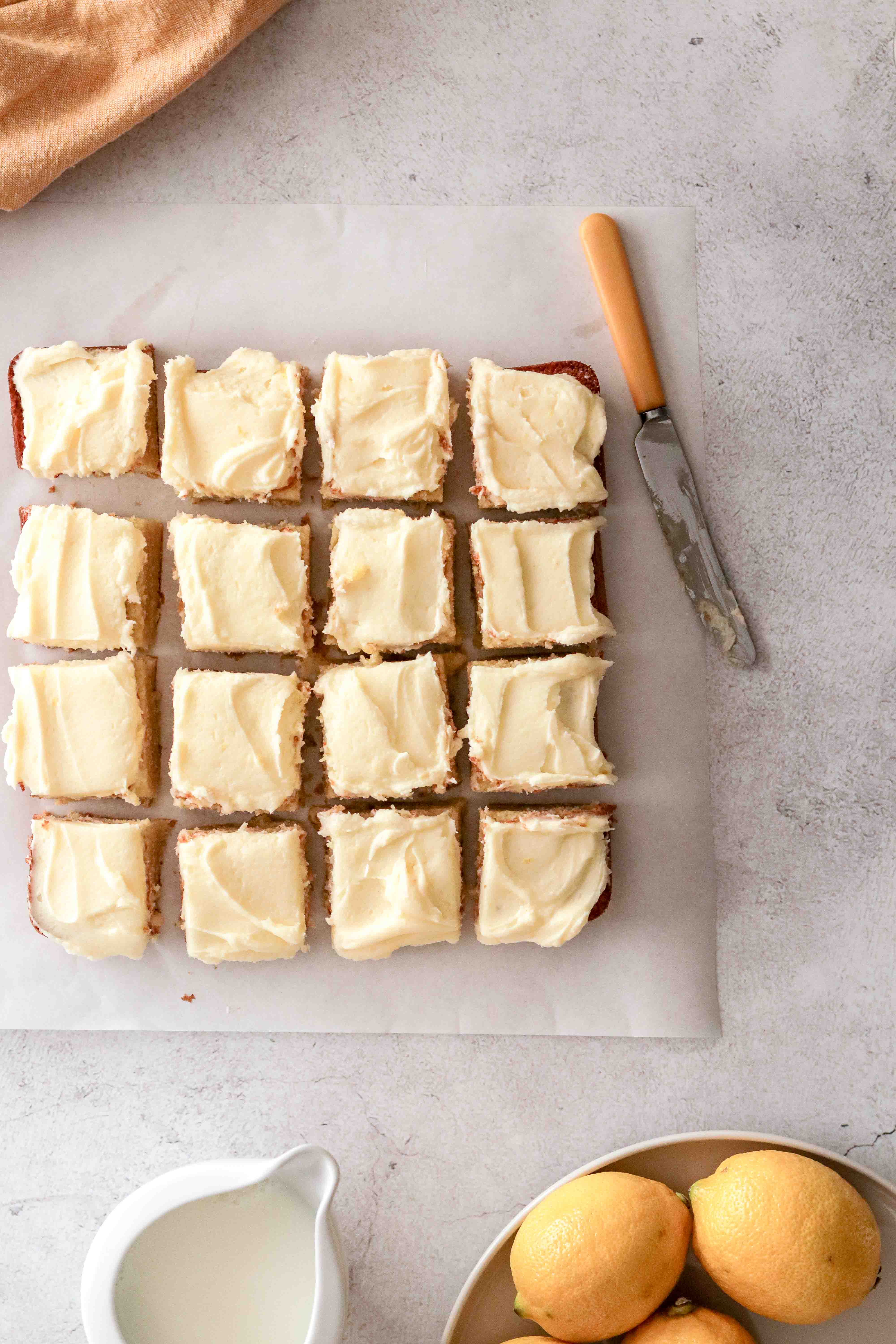 An iced lemon tray cake cut into squares