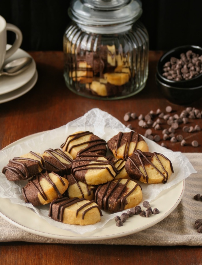 A plate of vanilla and chocolate almond butter cookies drizzled with chocolate. 