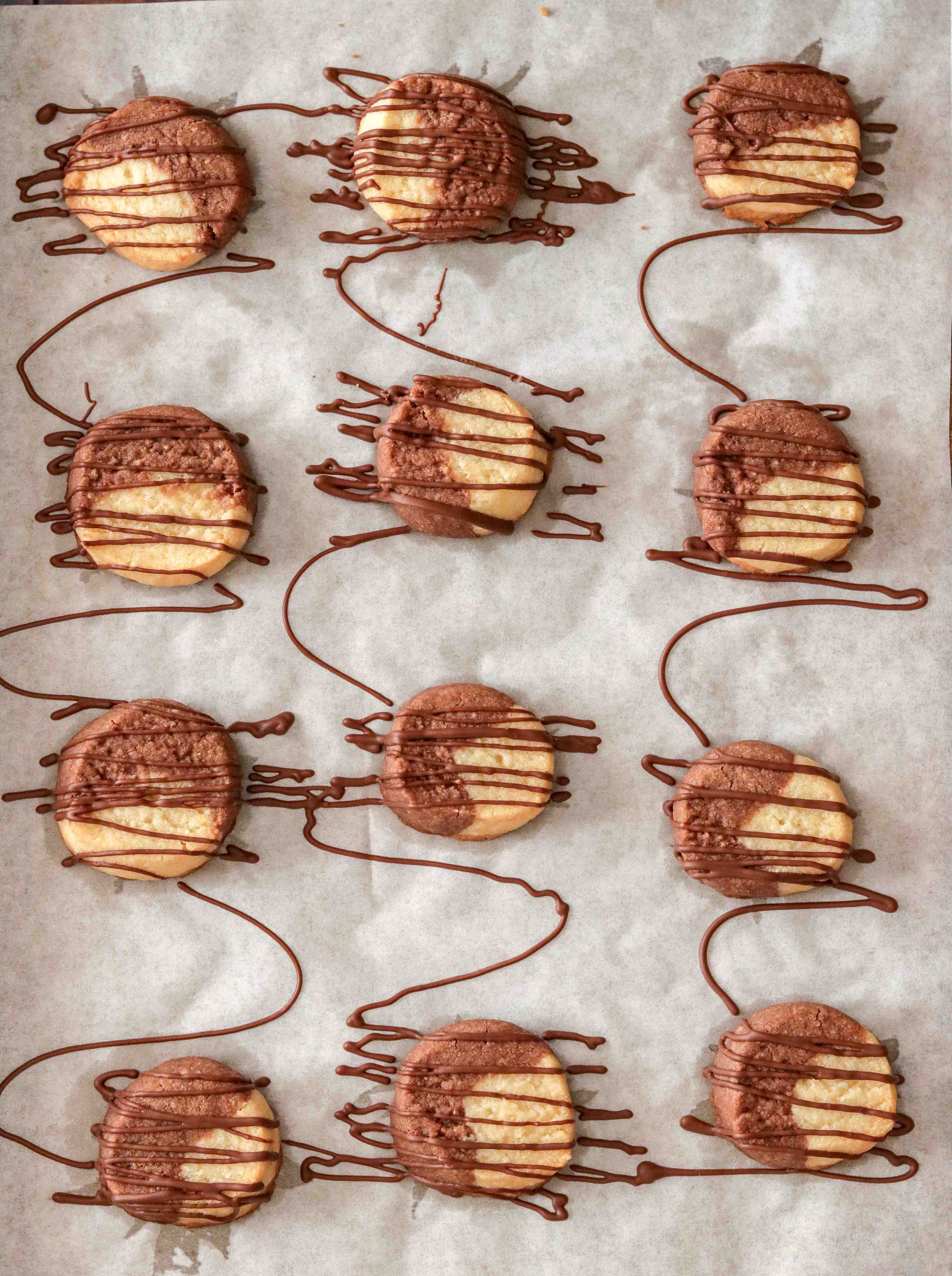 Top shot of cookies on a baking tray drizzled with chocolate 