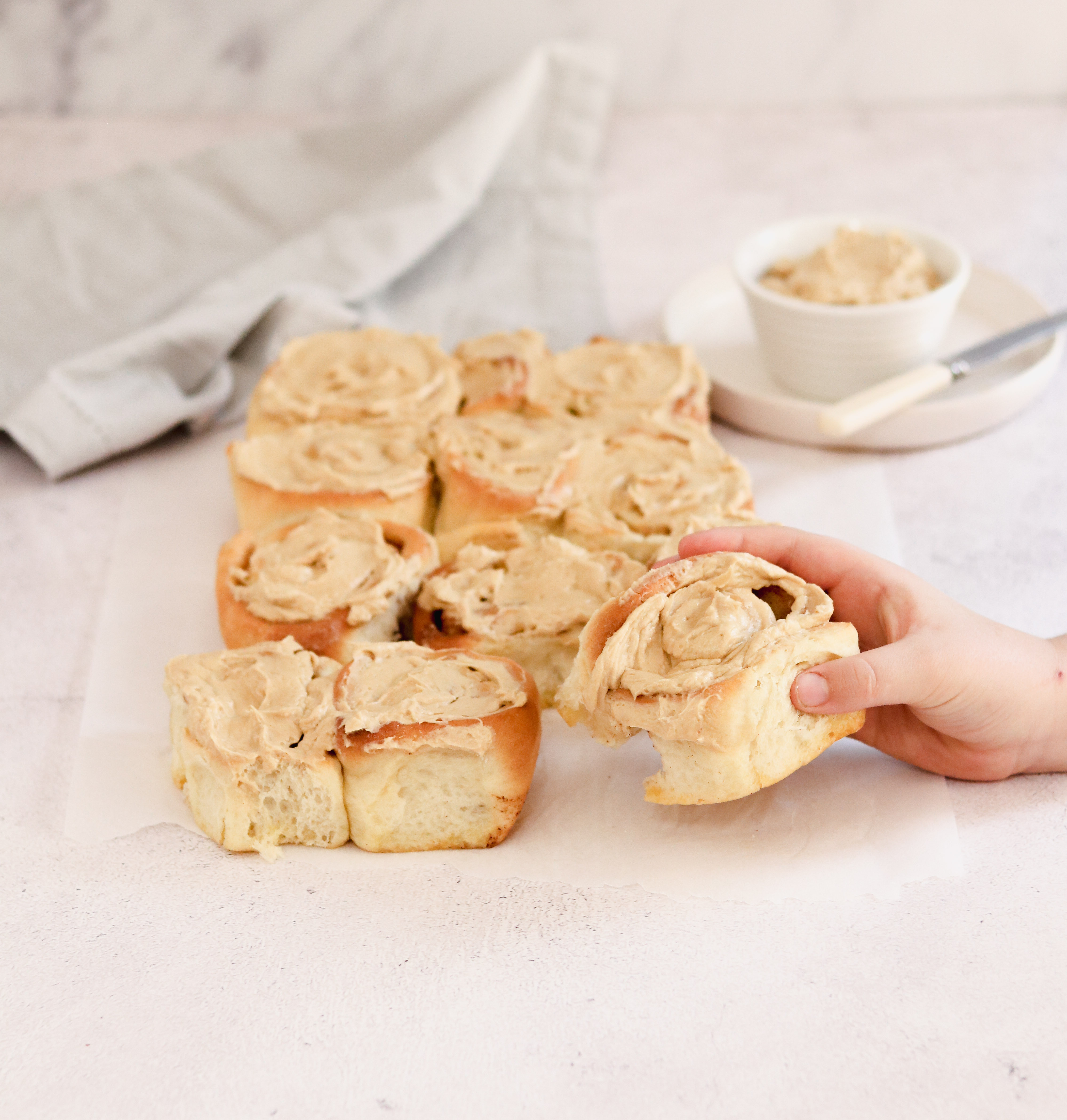 Child holding an apple and cinnamon bun with icing