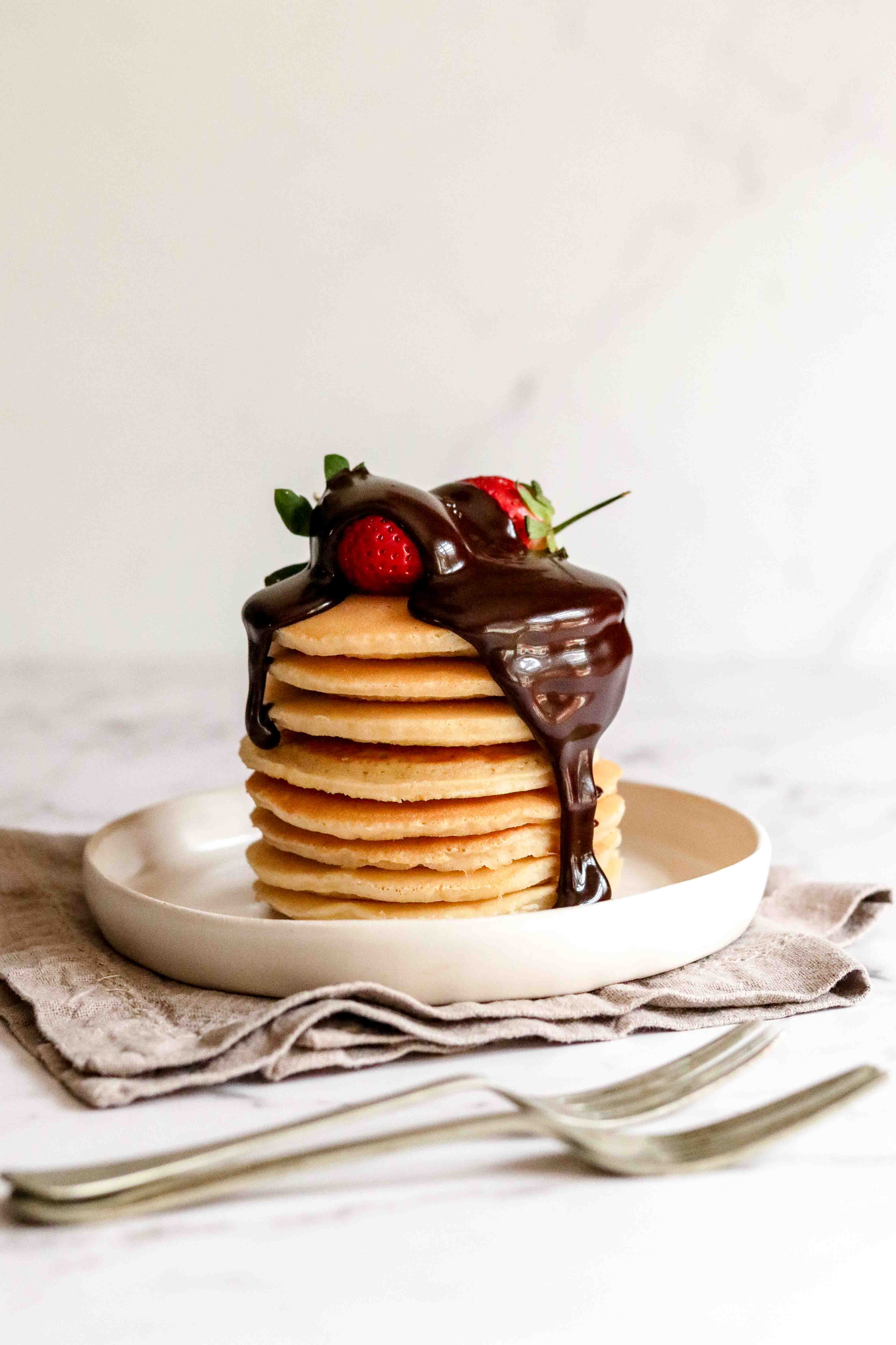 Sauce being poured over a stack of flapjacks